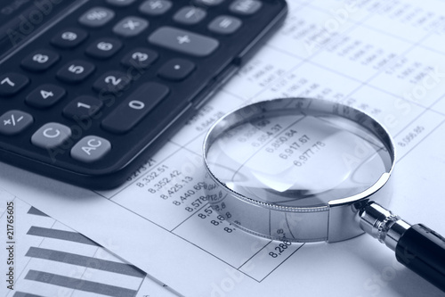 Magnifying glass with calculator on report.blue tone