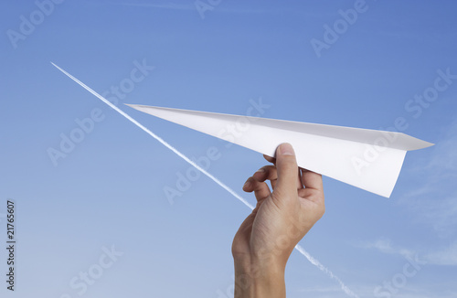 hand throwing a paper plane with jet-steam track on blue sky