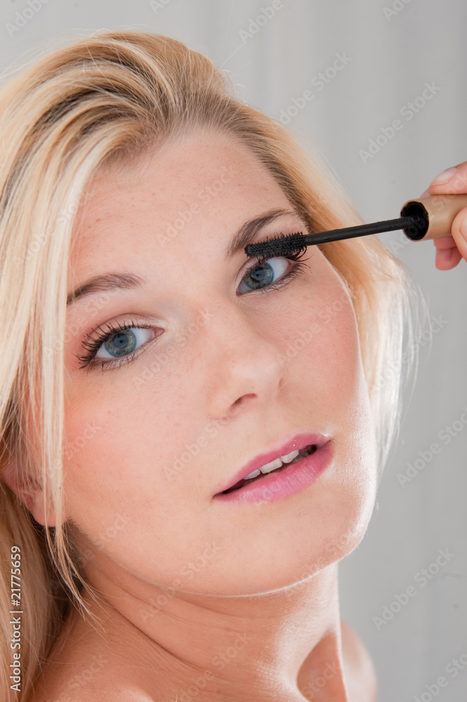 Beautiful woman applying mascara on her lashes