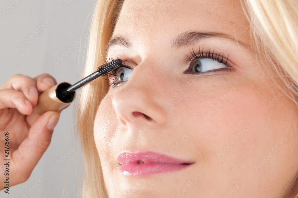 Beautiful woman applying mascara on her lashes