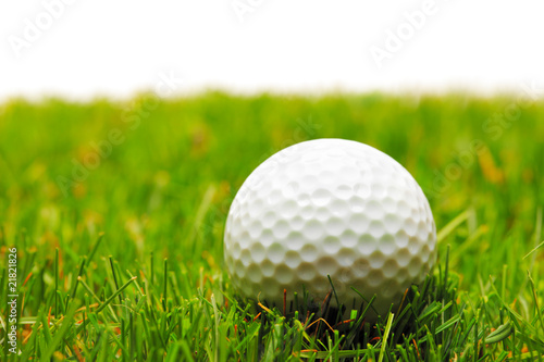 A golf ball on a green grass against white background