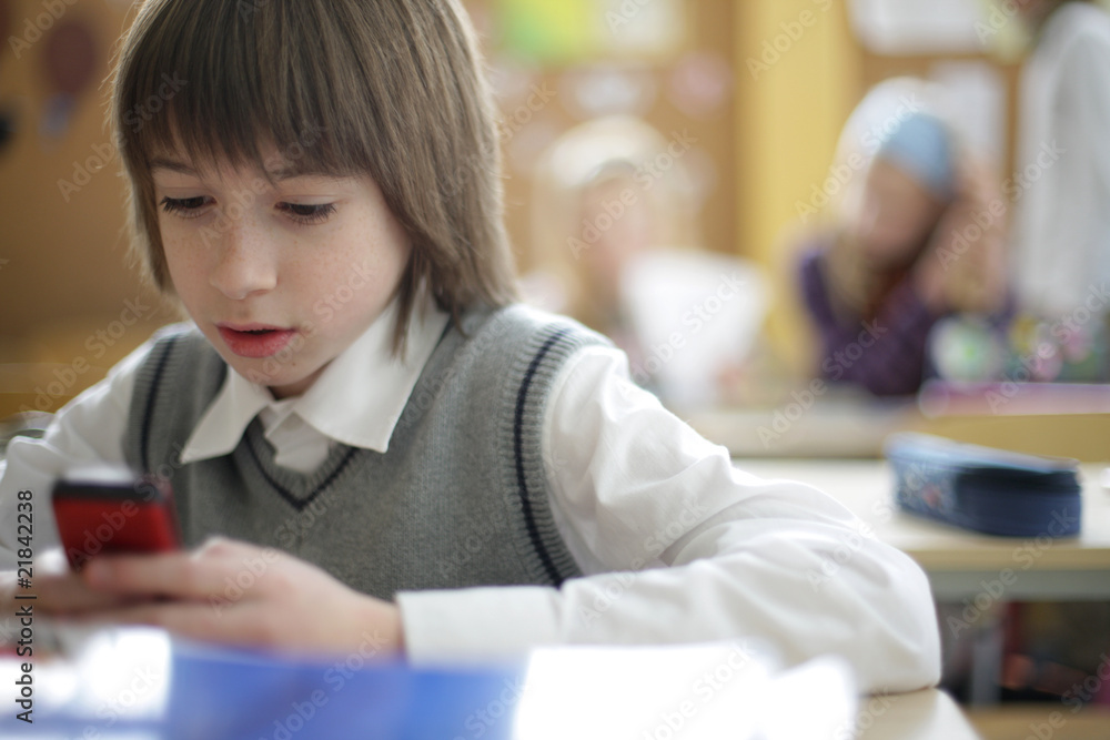 school pupil text messaging on cell phone in classroom school pupil text messaging on cell phone in classroom