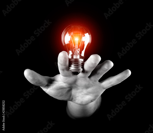Hand holding light bulb isolated on black.
