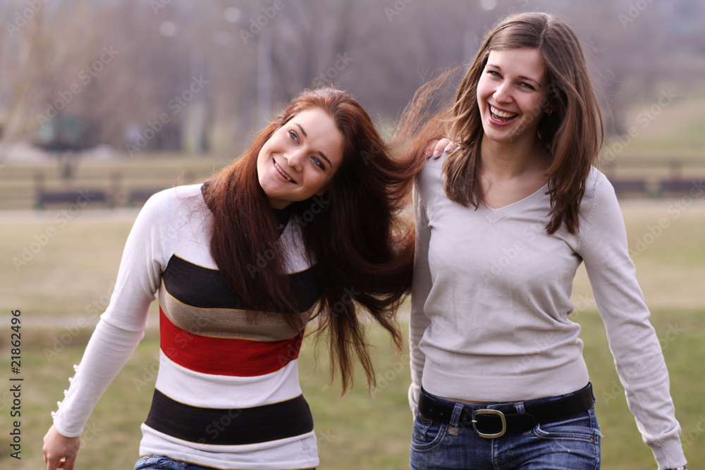 Obraz premium Two cheerful walking girls in the park