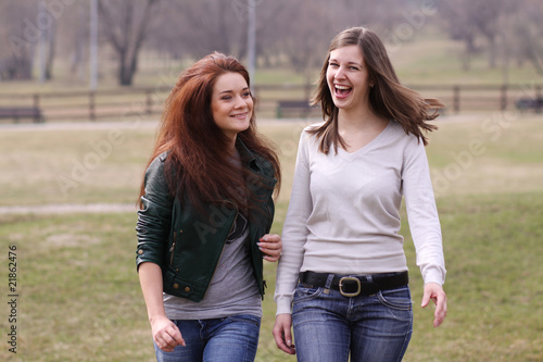 Two cheerful walking girls in the park