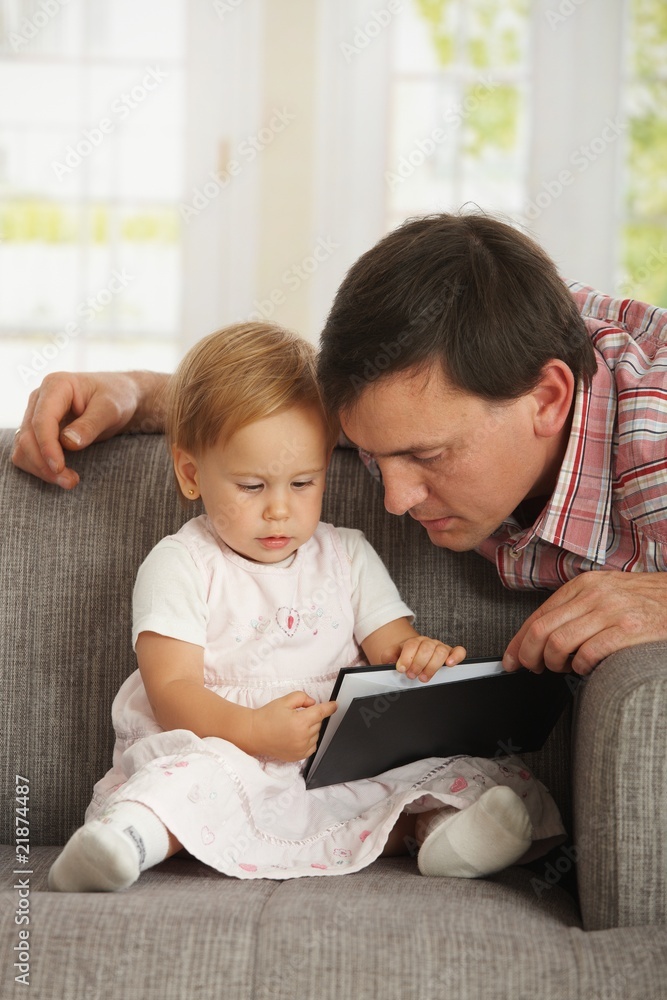 Father and toddler reading book on sofa Father and toddler reading book on sofa