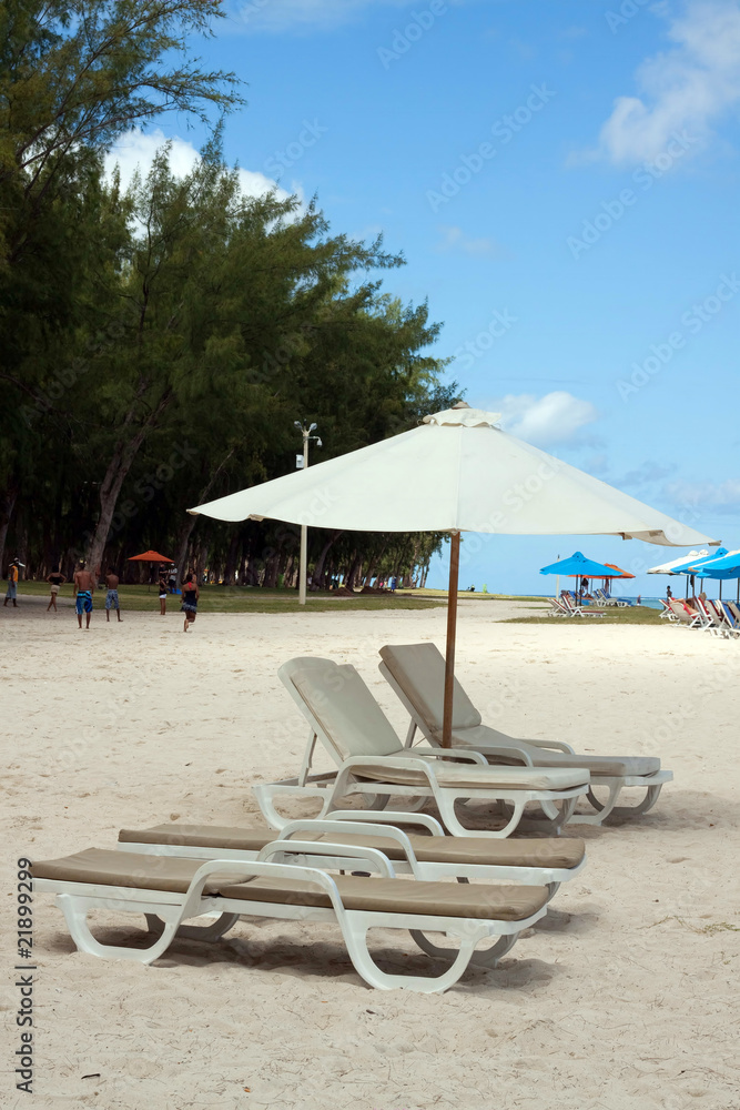 reclining chairs under the shadow of beach umbrella.