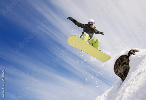 Snowboarder jumping through air with  blue sky in background