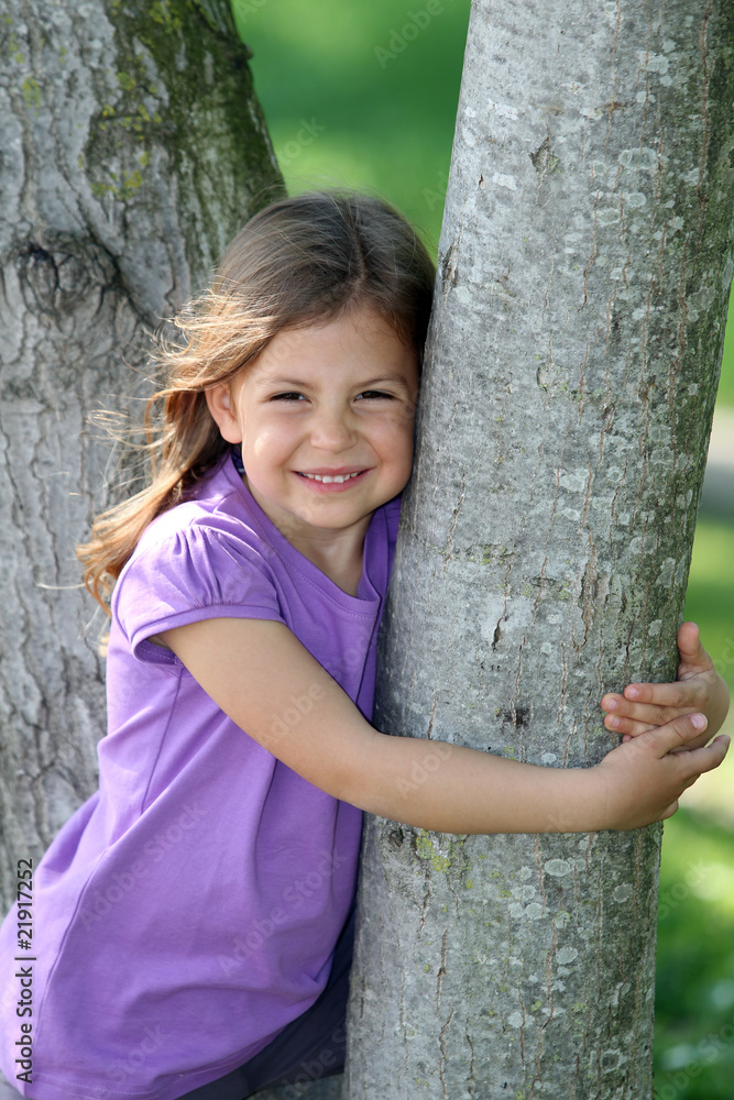 Cute young girl smiling and hugging a tree Cute young girl smiling and hugging a tree