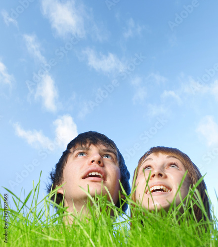 Two human heads stick out from green grass on blue sky background photo