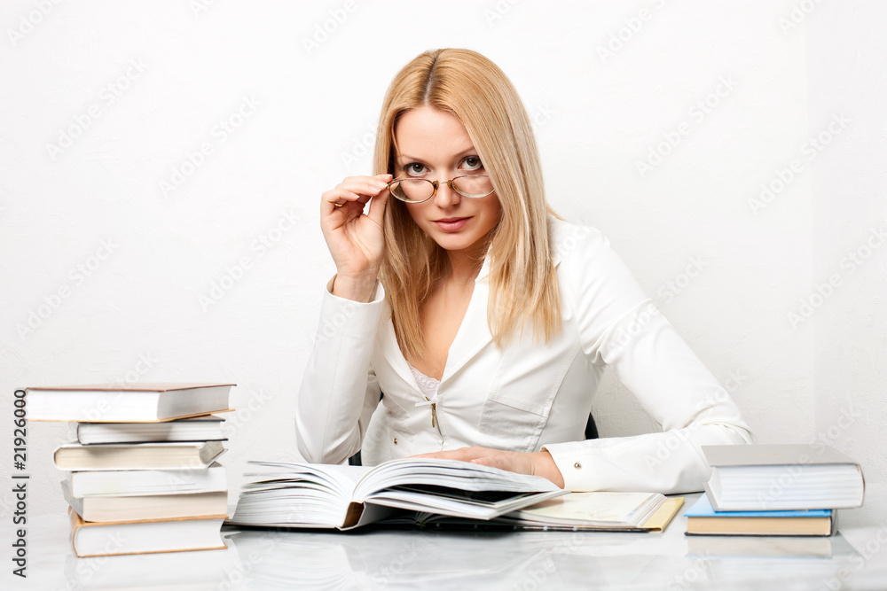 Young woman wearing glasses at table with books Young woman wearing glasses at table with books
