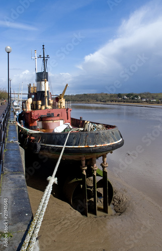 Old tug boat moored by the side of a river