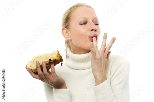 young woman wearing a white sweater eating a slice of panettone