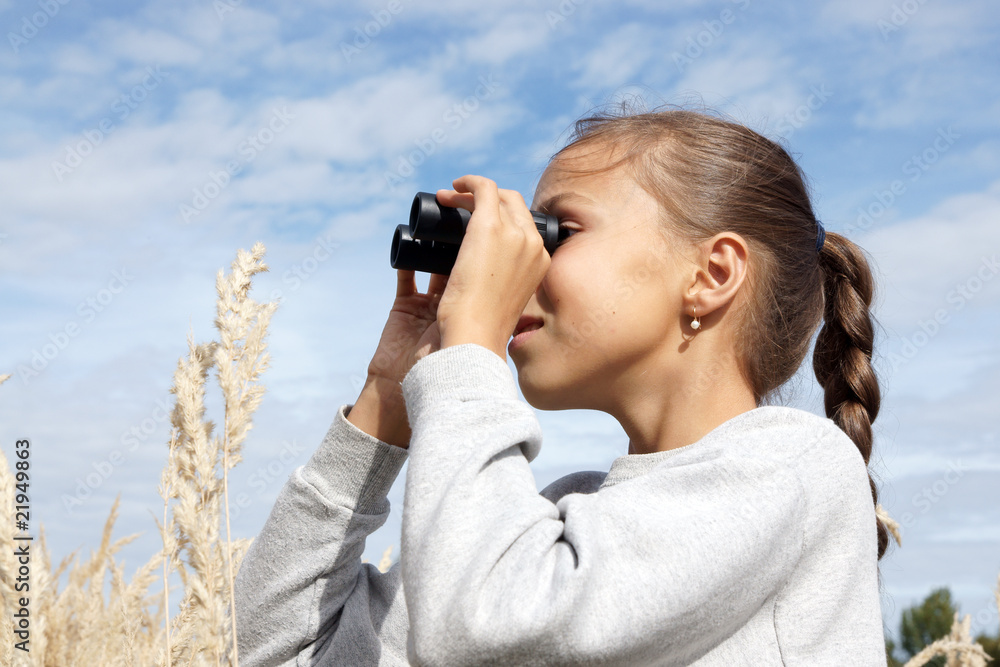 Preteen girl looking at far with binoculars outdoors