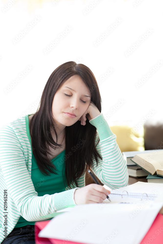 Tired young student sleeping while doing her homework Tired young student sleeping while doing her homework