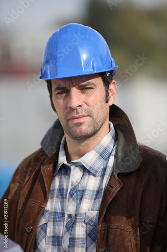 portrait d'un ouvrier avec casque de chantier bleu © auremar