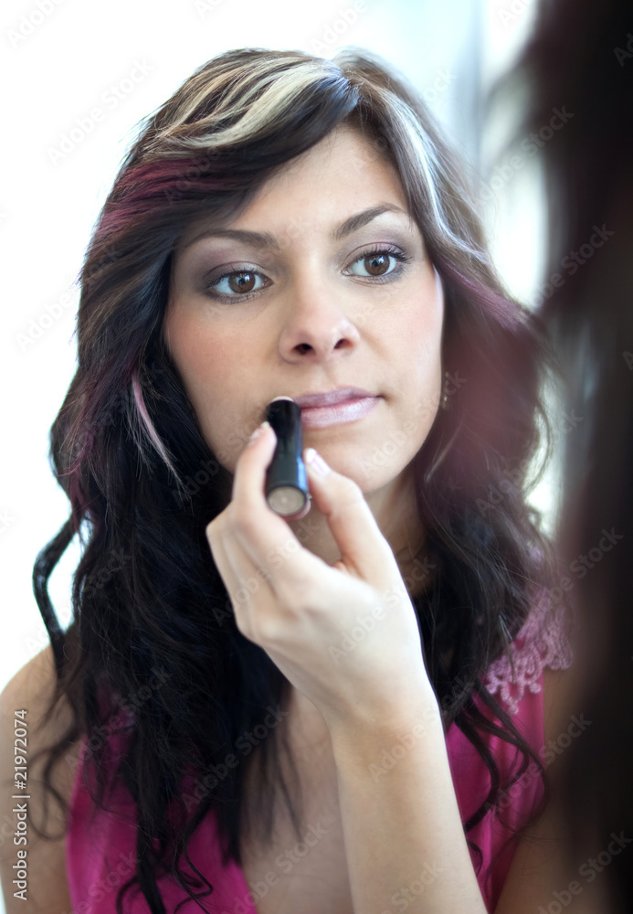 pretty young woman applying mascara./eyeshadows in front of a mi pretty young woman applying mascara./eyeshadows in front of a mi