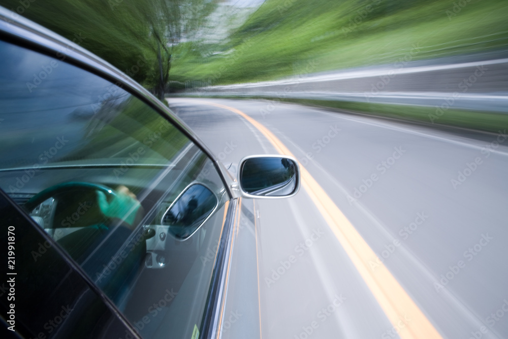 The car moves at great speed at the sunny day.