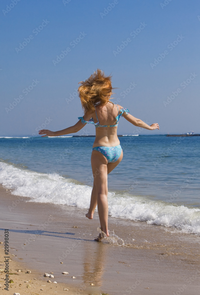 Naklejka premium Young graceful woman goes on coast of ocean