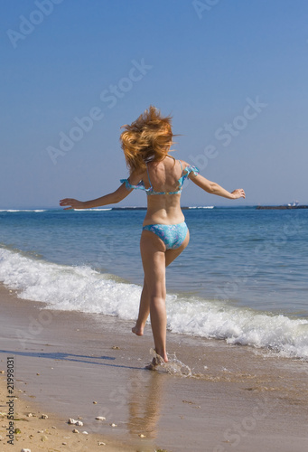 Young graceful woman goes on coast of ocean