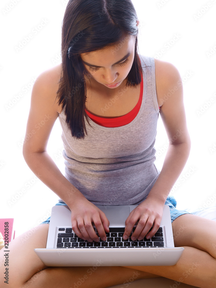 Naklejka premium young student sitting with crossed legs working on notebook