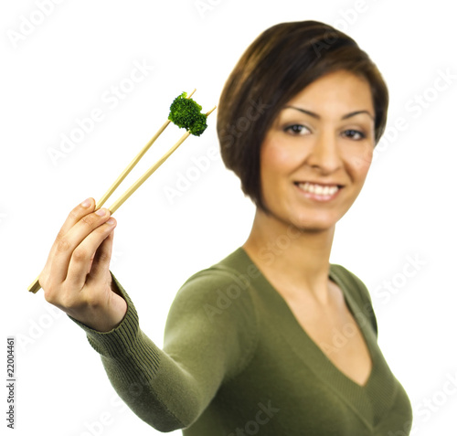 Smiling young woman holds a piece of green broccoli with chopsti photo