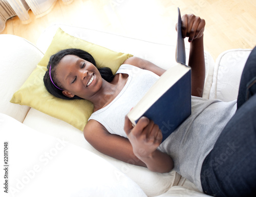 Smiling woman reading lying on a sofa