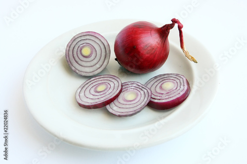 Sliced onion on saucer and an onion bulb on a white background