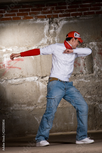 Hip hop boy dancing in modern style over grey brick wall