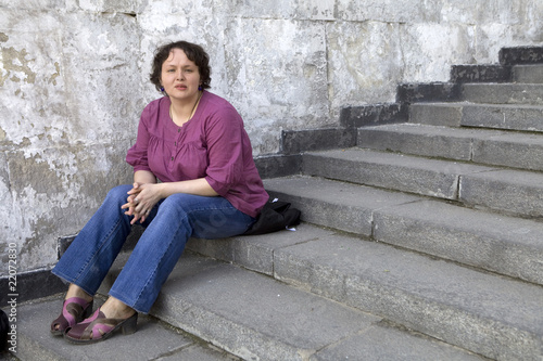 serious curl woman sitting on stairs