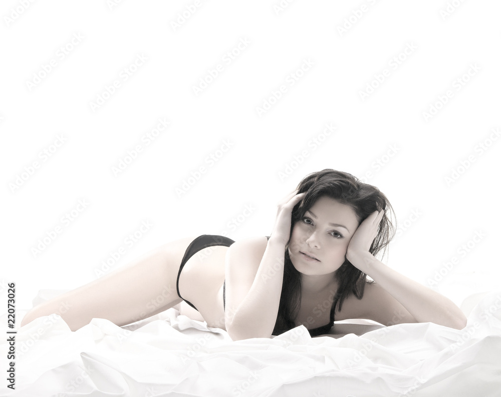 Naklejka premium A young and sexy brunette lying on a bed