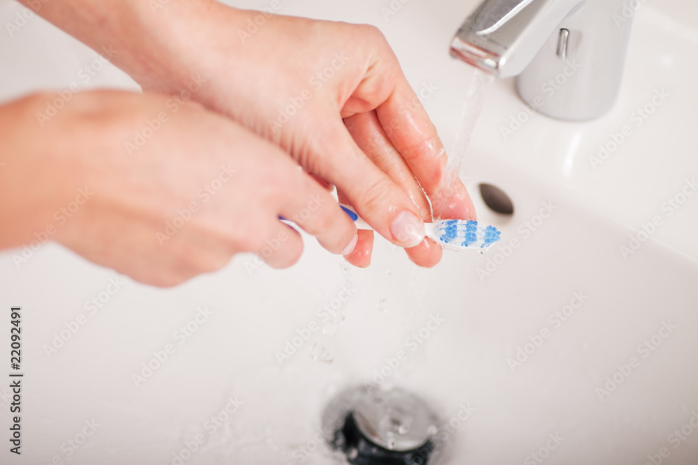 Junge Frau (nur Hände) säubert die Zahnbürste