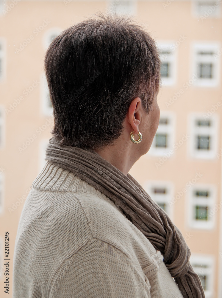 Seniorin steht einsam, deprimiert, traurig bei Fenster Seniorin steht einsam, deprimiert, traurig bei Fenster
