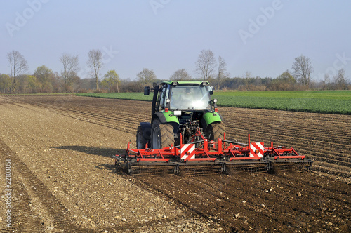 Bauer mit Traktor auf Feld im Frühjahr