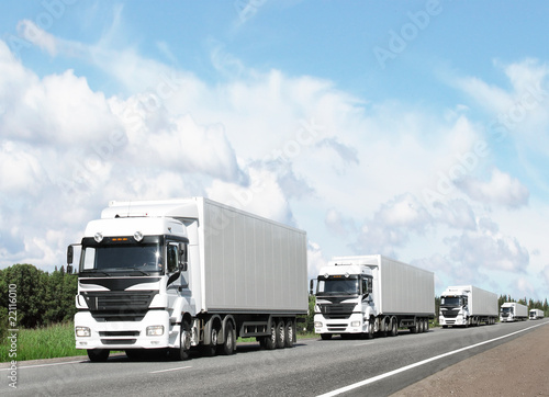 caravan of white trucks on highway, light sky