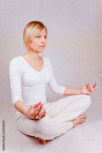 young woman practicing yoga - front-side view on white