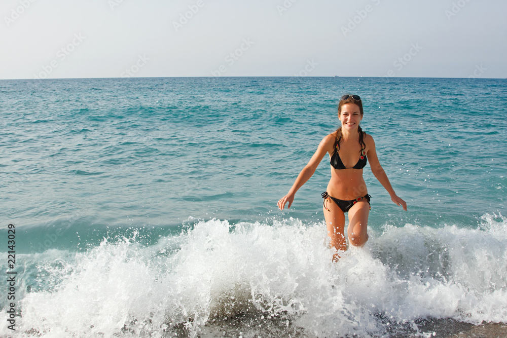 Fototapeta premium Young woman playing with waves on the beach