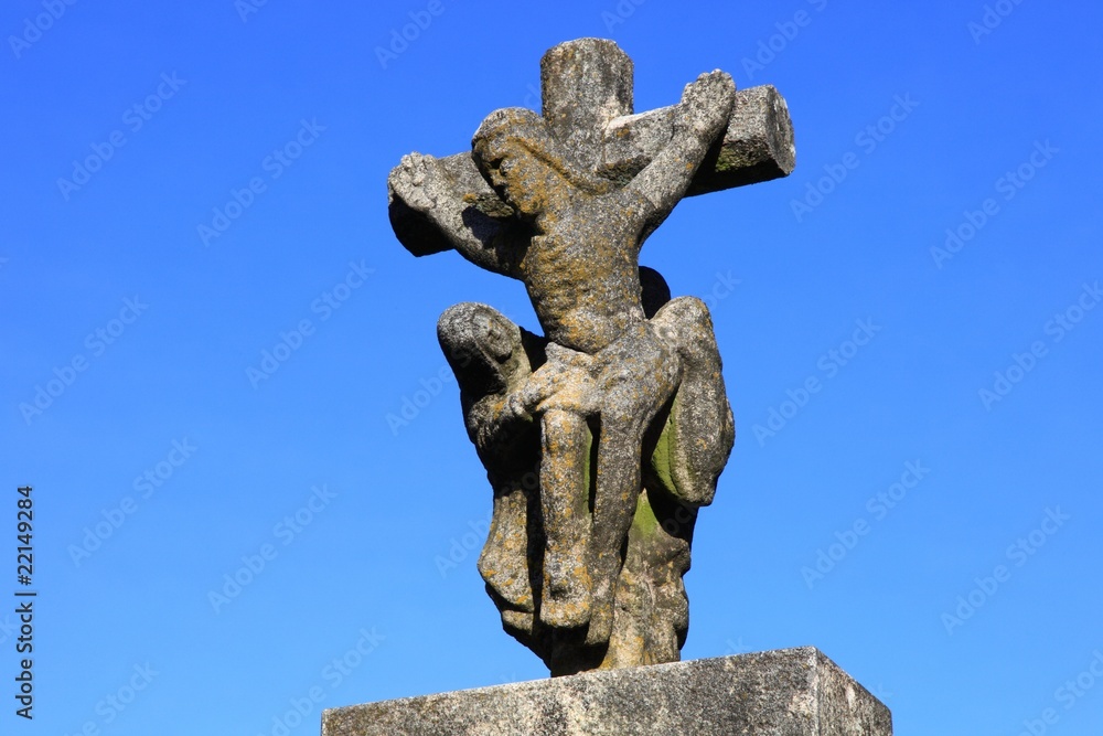 Jesus Christus am Kreuz, Steinfigur vor blauem Himmel Jesus Christus am Kreuz, Steinfigur vor blauem Himmel
