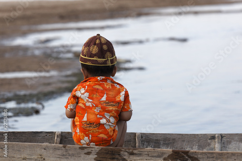 Petit enfant assis sur le bord d'une pirogue