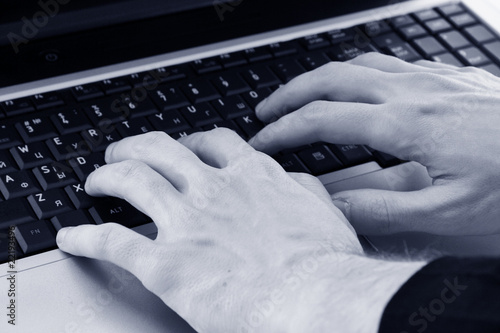 Closeup of male fingers typing a document on the black laptop.