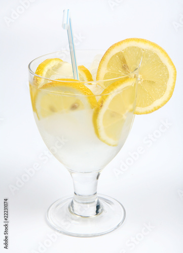 Water with lemon slices, ice and a straw in a glass cup