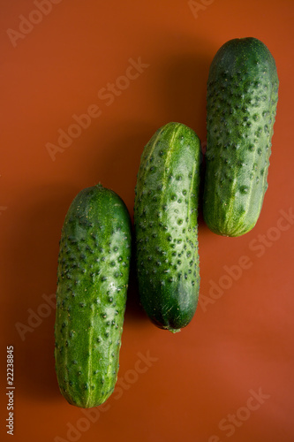 three green bumps cucumbers on a red background