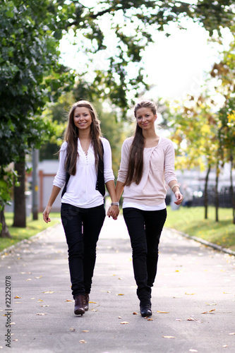 Fashionable girls twins walk in the street