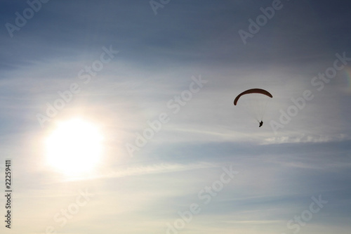 Paraglider flying towards the sun
