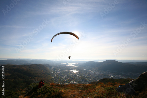 Paraglider flying over Norwegian coastal landscape