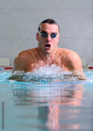 man swims using the breaststroke in indoor pool © Sergey Peterman