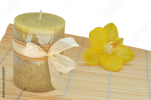 Spa candle on bamboo mat with yellow orchid