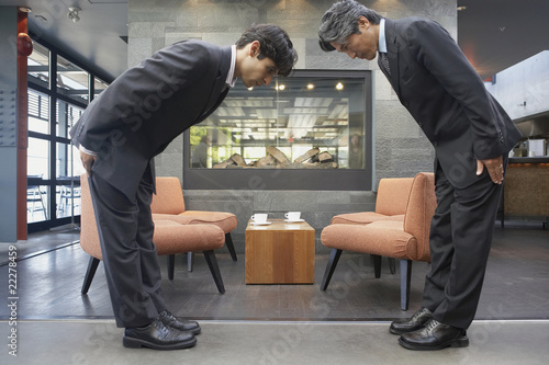 Two businessmen bowing to each other in cafe