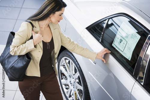 Hispanic woman looking at new car photo