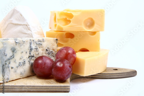 Various types of cheese and some red grapes in close up